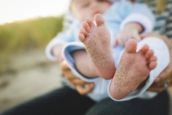 baby's feet covered in sand