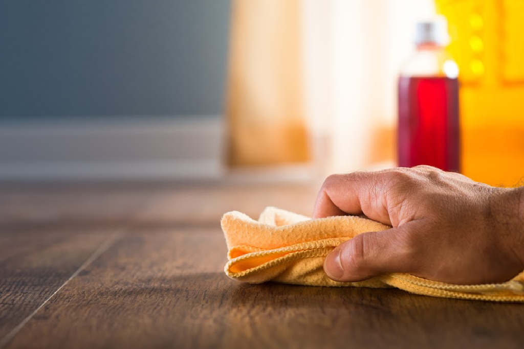 Male hand applying wood cleaner with a cloth